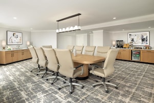 A conference room with a round table, six chairs, a modern chandelier, and artwork on the walls.