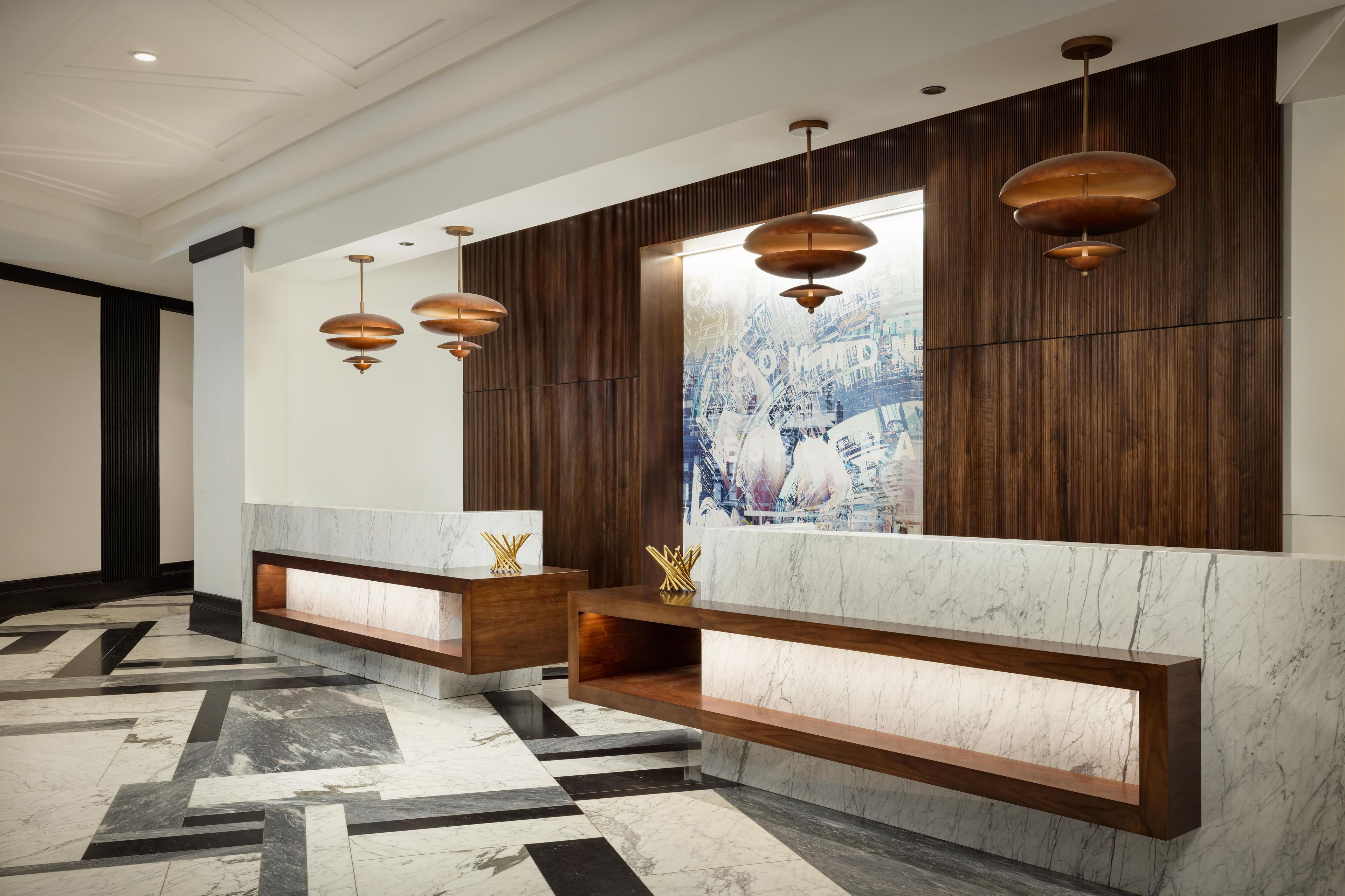 A reception area with marble counters, wooden shelving, and pendant lighting.