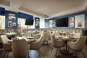 Un restaurant avec un mur bleu, des tableaux encadrés et un téléviseur à écran plat.