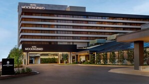 Un hotel moderno con techo plano, varios pisos y una entrada destacada.