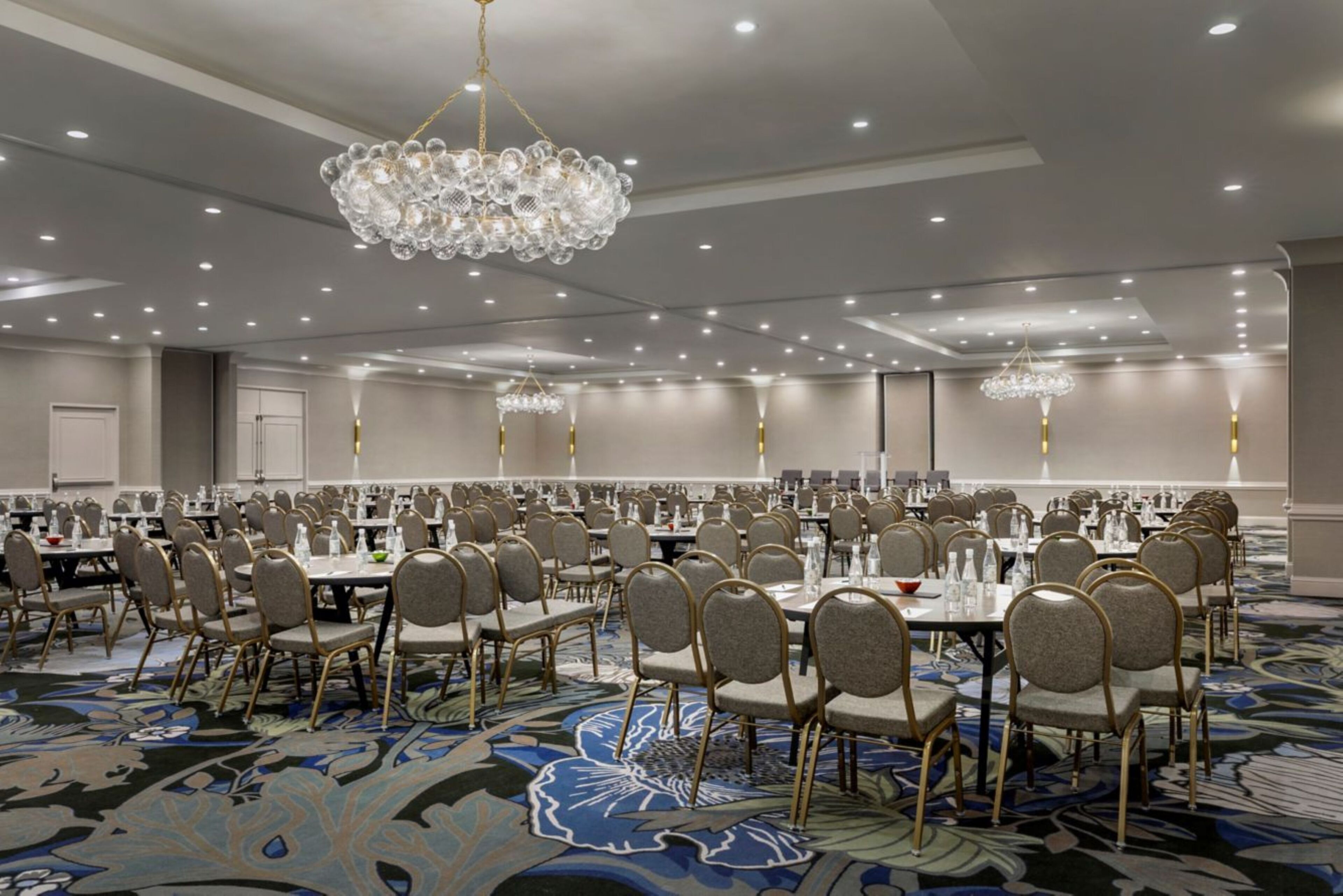 Un amplio salón de banquetes con mesas redondas, sillas y candelabros.