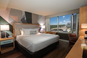 A hotel room with a large bed, two bedside tables with lamps, a desk with a chair, and a large window offering a city view. - Hotel Mockingbird, Dallas, A Tribute Portfolio Hotel (Dallas)