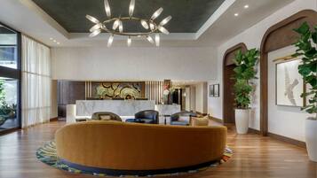 A modern lobby with a round seating area, a chandelier, and large windows.