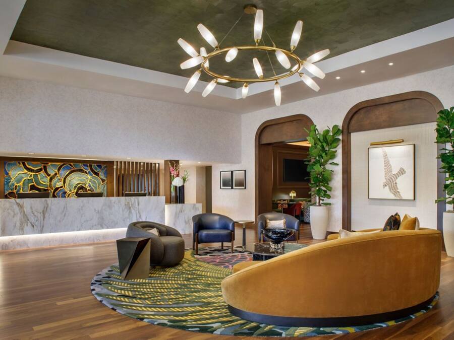 Um hall moderno com uma recepção de mármore, uma área de estar circular e um grande candelabro.