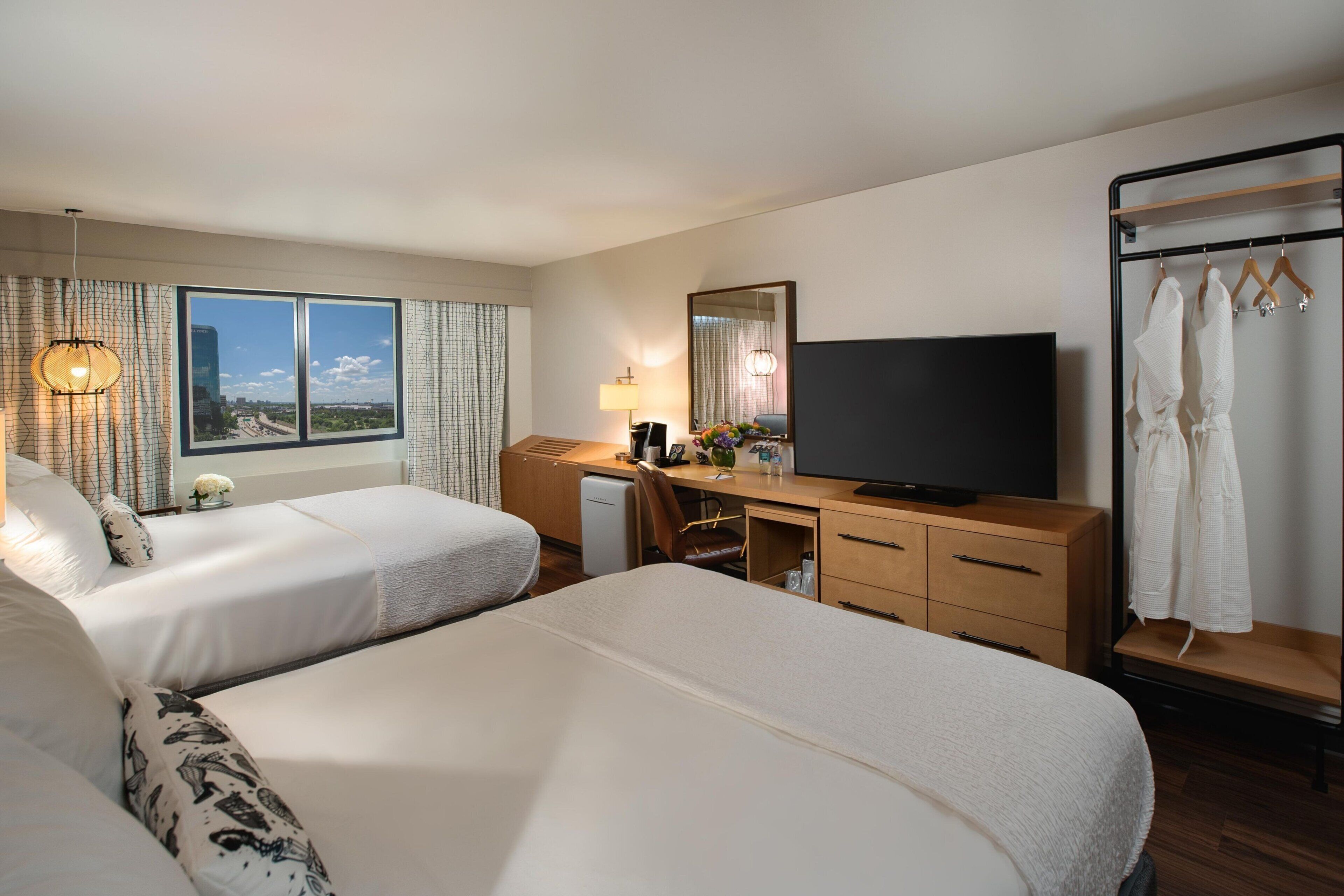 Ett hotellrum med två sängar, ett skrivbord, en tv och en garderob.