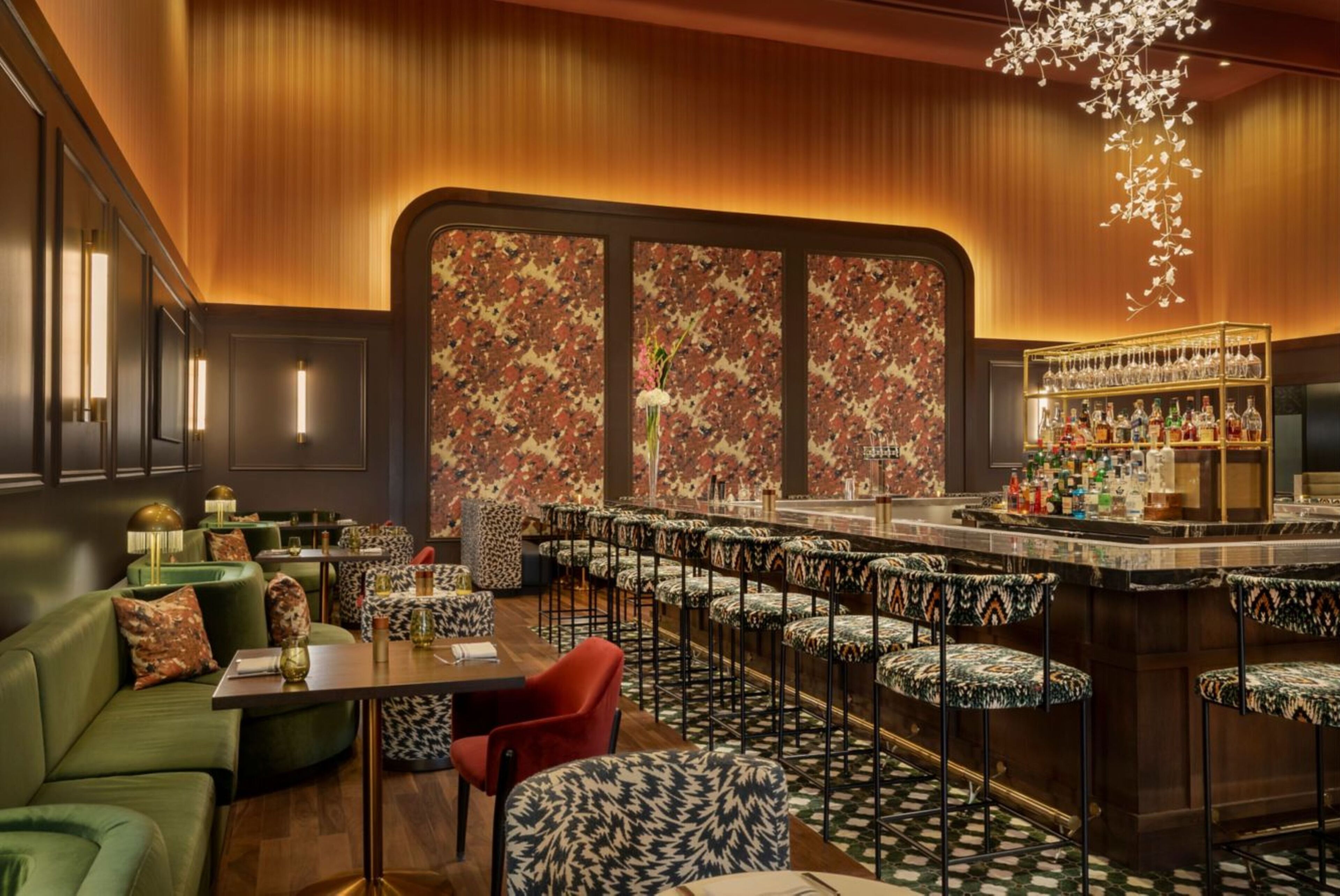 A bar area with a long counter, multiple stools, and a patterned wall.