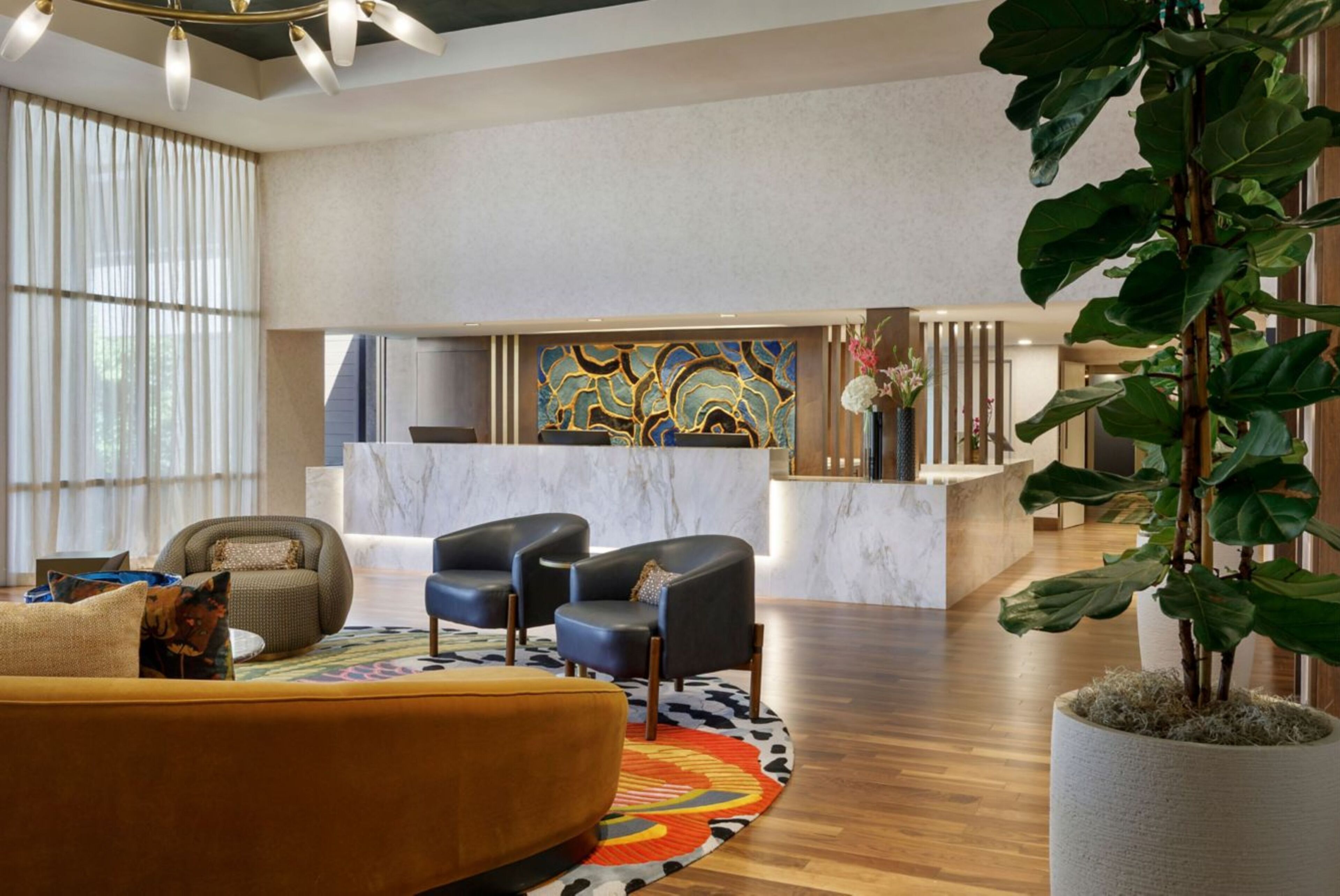 A hotel lobby with a reception desk, seating area, and a large plant.