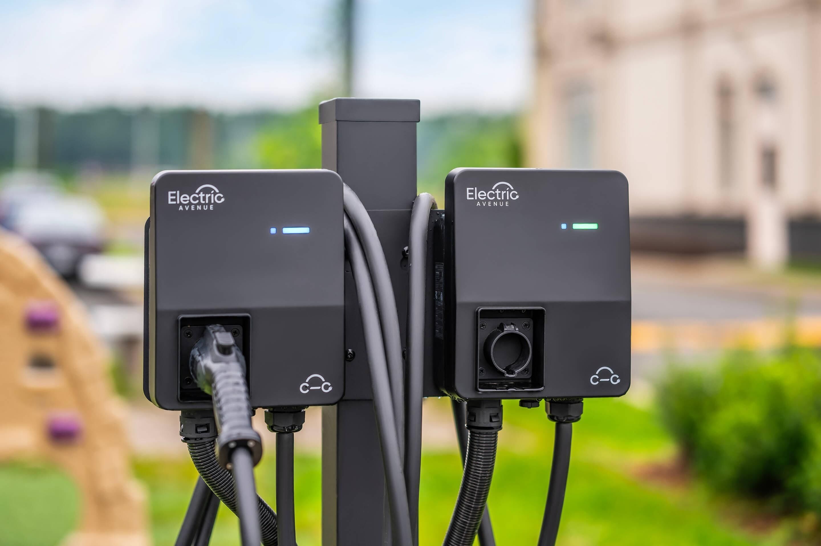 Two electric vehicle charging stations labeled "Electric Avenue" with cables connected to them.