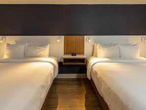 A hotel room with two beds, a wooden headboard, bedside tables, and a clock.