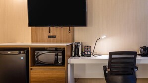A hotel room with a flat-screen TV mounted on the wall, a microwave, a coffee maker, and a desk with a chair. - Comfort Inn Rouyn Noranda (Rouyn-Noranda)