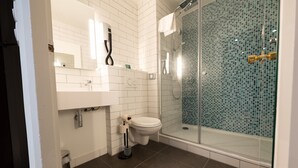 A modern bathroom with a toilet, sink, and glass shower enclosure.