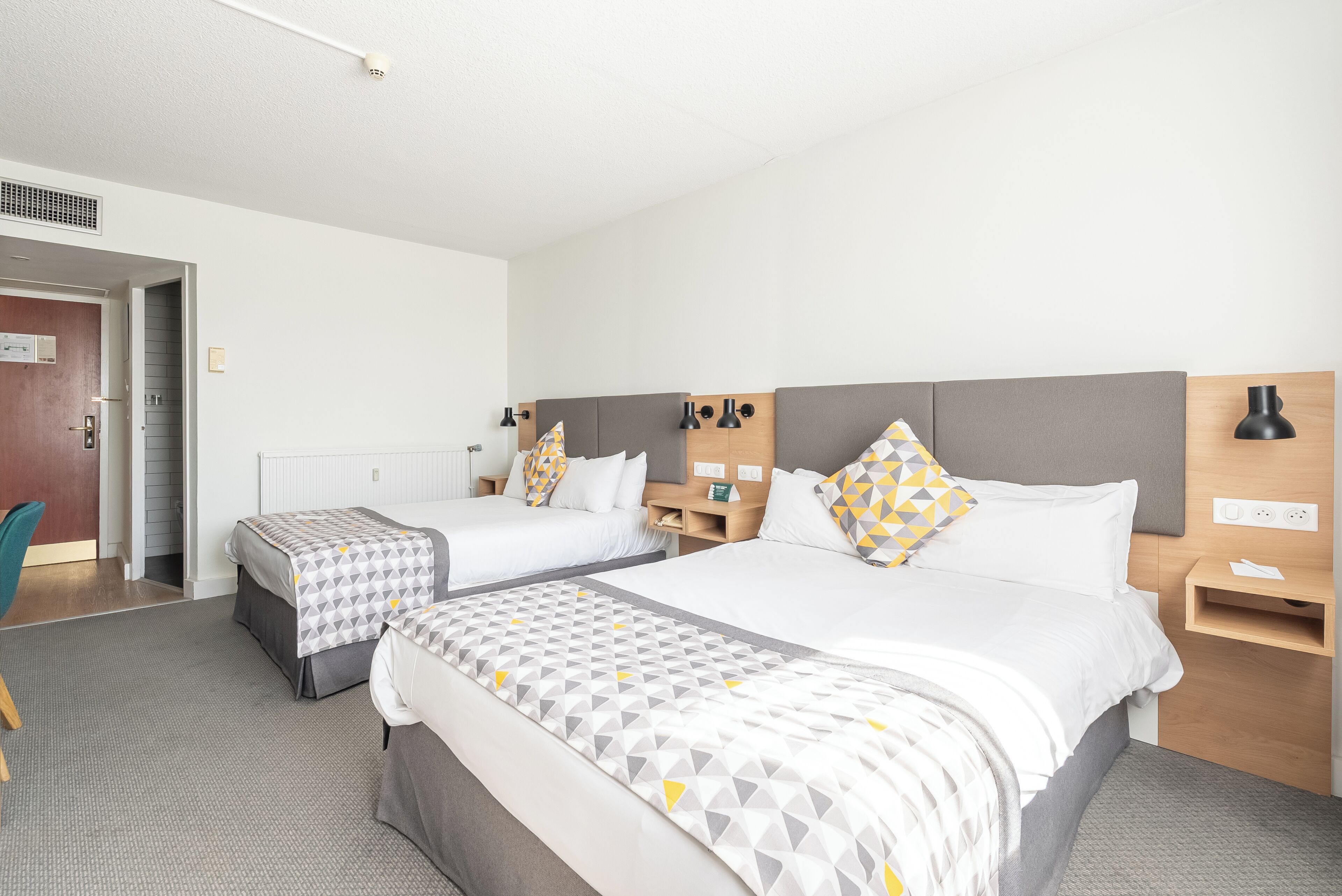 Ein Hotelzimmer mit zwei Betten, einem Schreibtisch, einem Stuhl und einem kleinen Tisch.