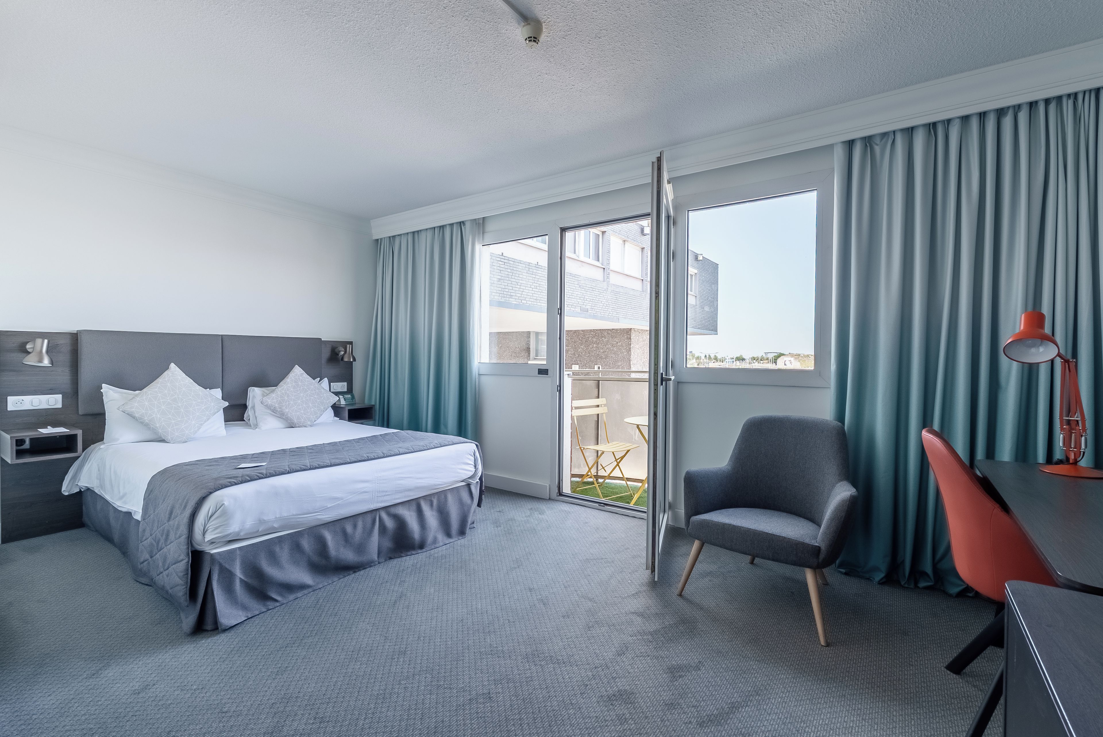 Een hotelkamer met een bed, een bureau, een stoel en uitzicht.