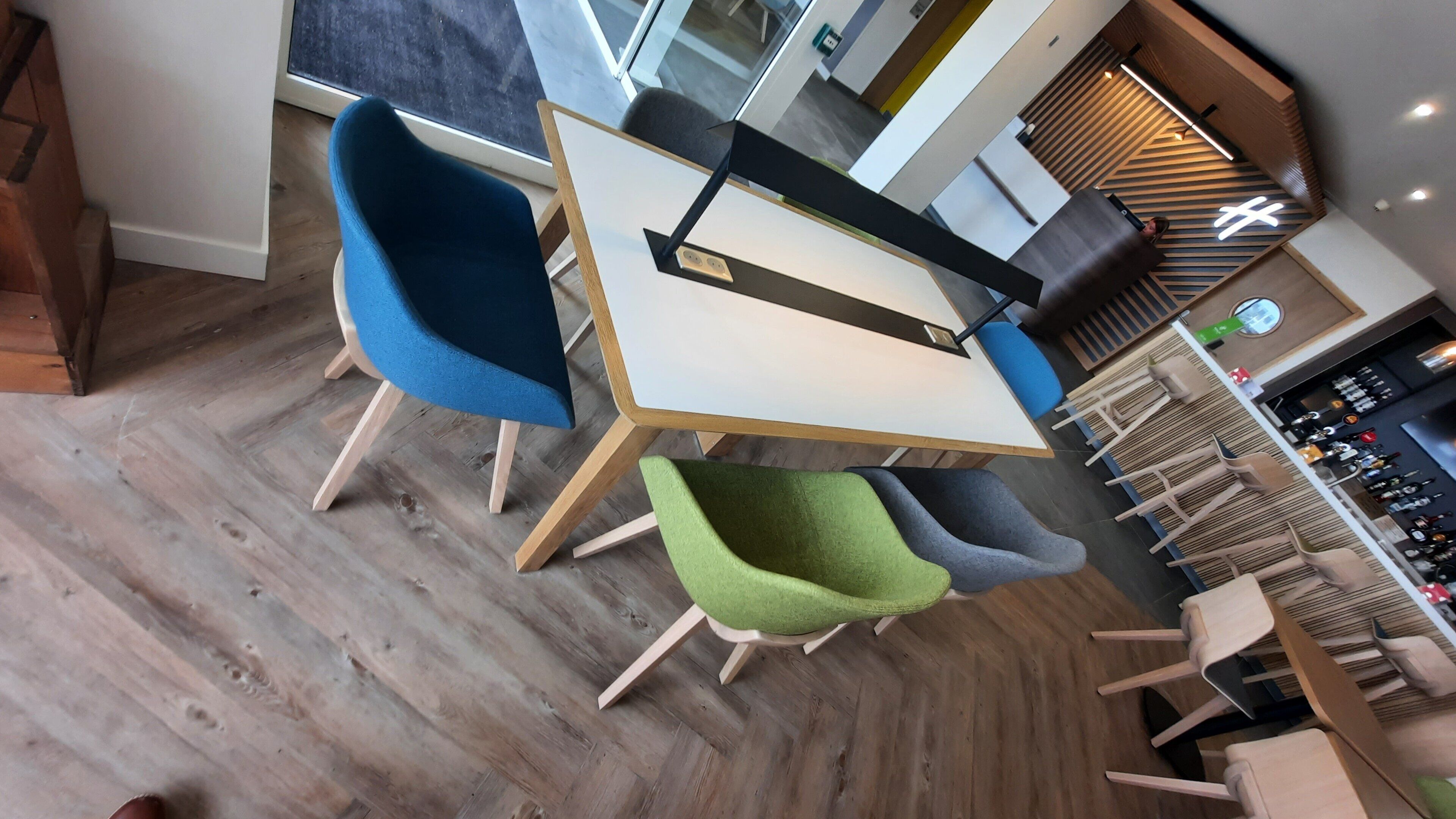 Een moderne eetruimte met een houten tafel en stoelen, een bar met krukjes, en een visgraatvloer.