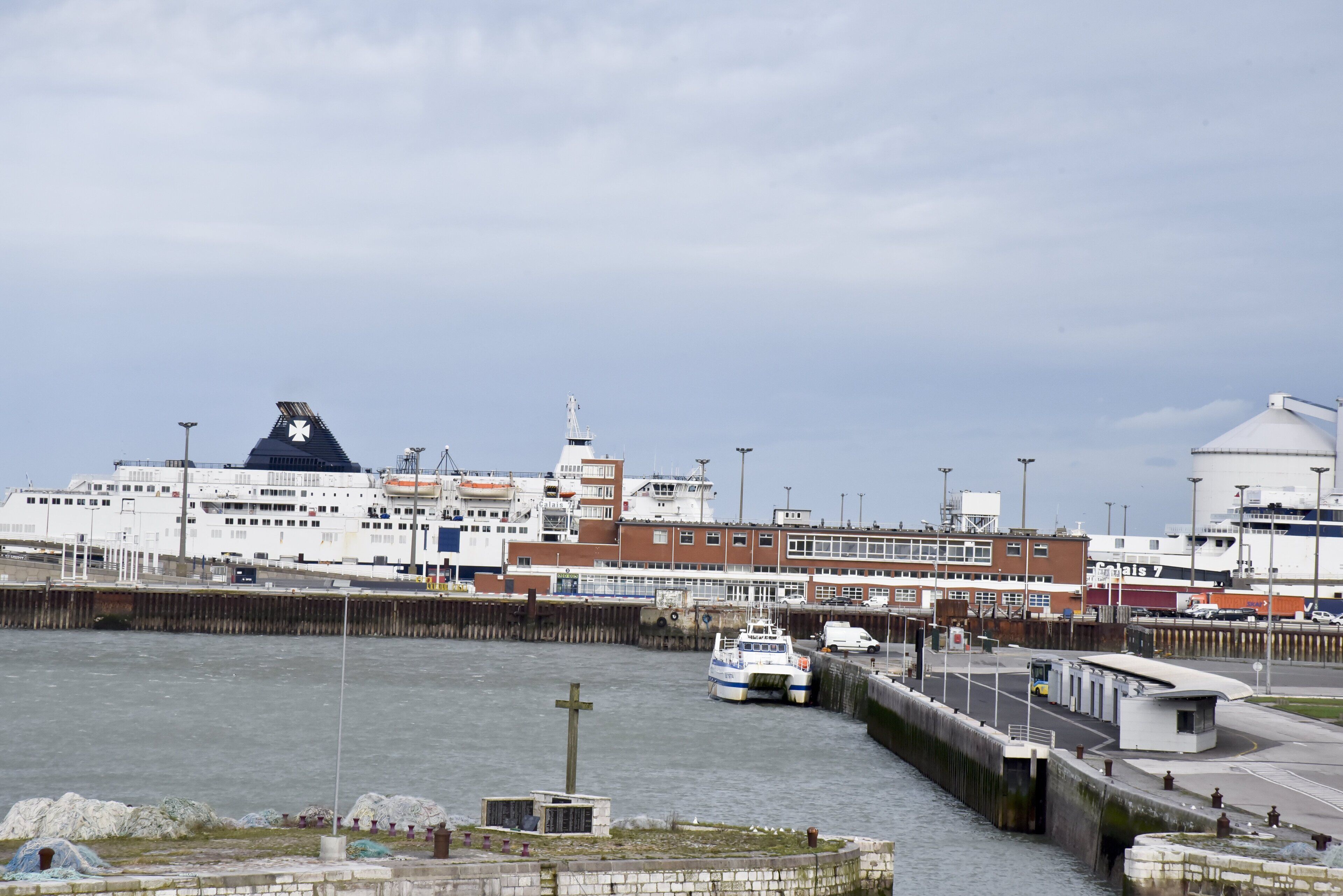 A waterfront area with a large cruise ship docked, a small boat, and a building with a dome.