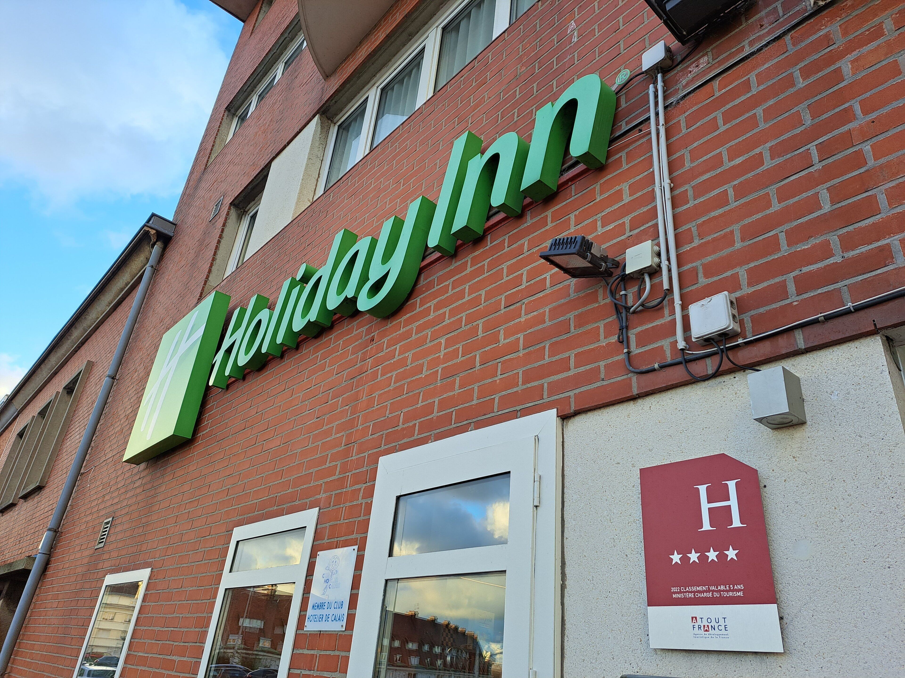 Een Holiday Inn bord aan een bakstenen gebouw met een heldere lucht.