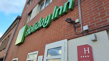 Een Holiday Inn bord aan een bakstenen gebouw met een heldere lucht.