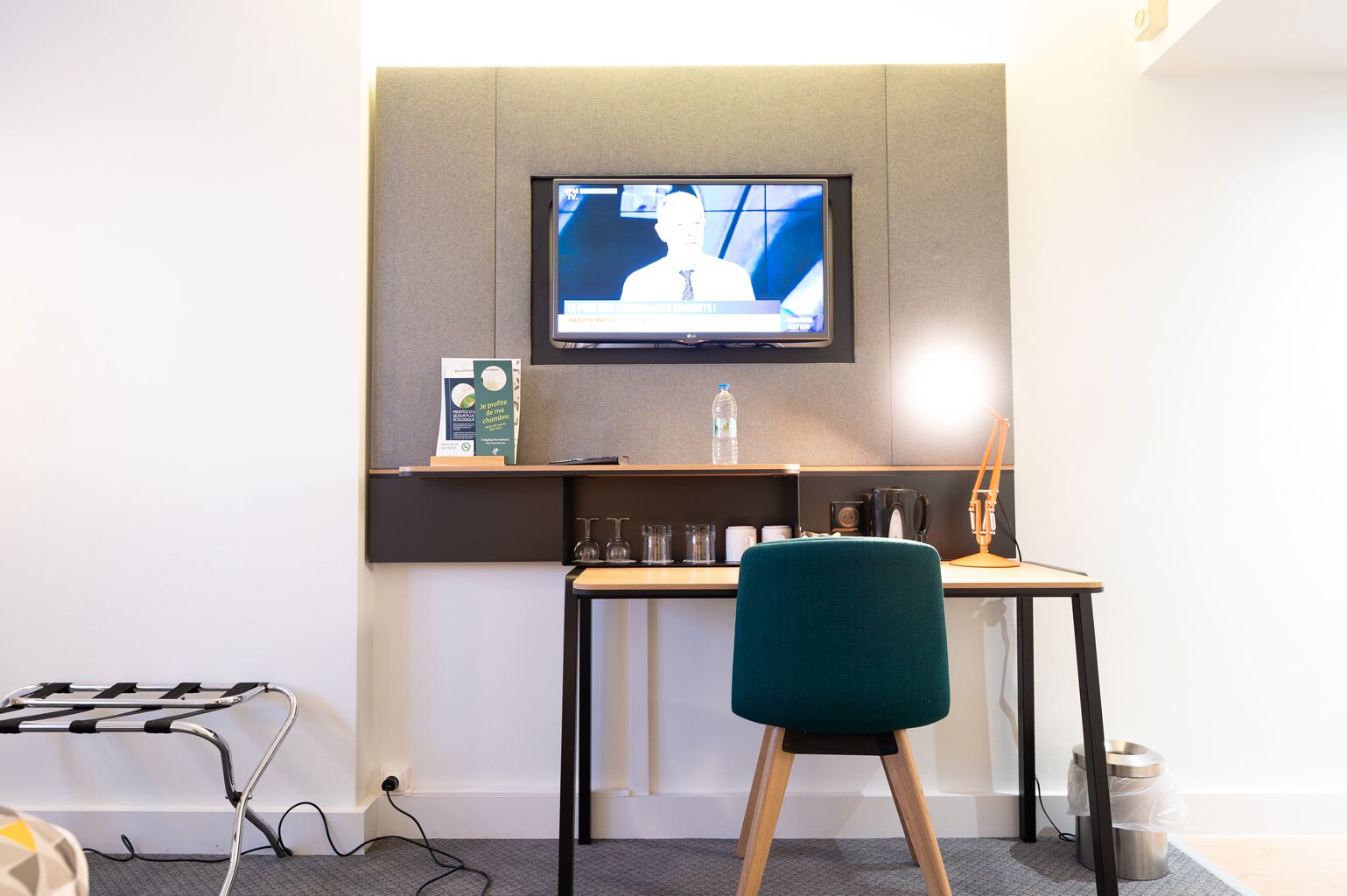 Een moderne kantoorruimte met een bureau, stoel en een wandgemonteerde televisie.