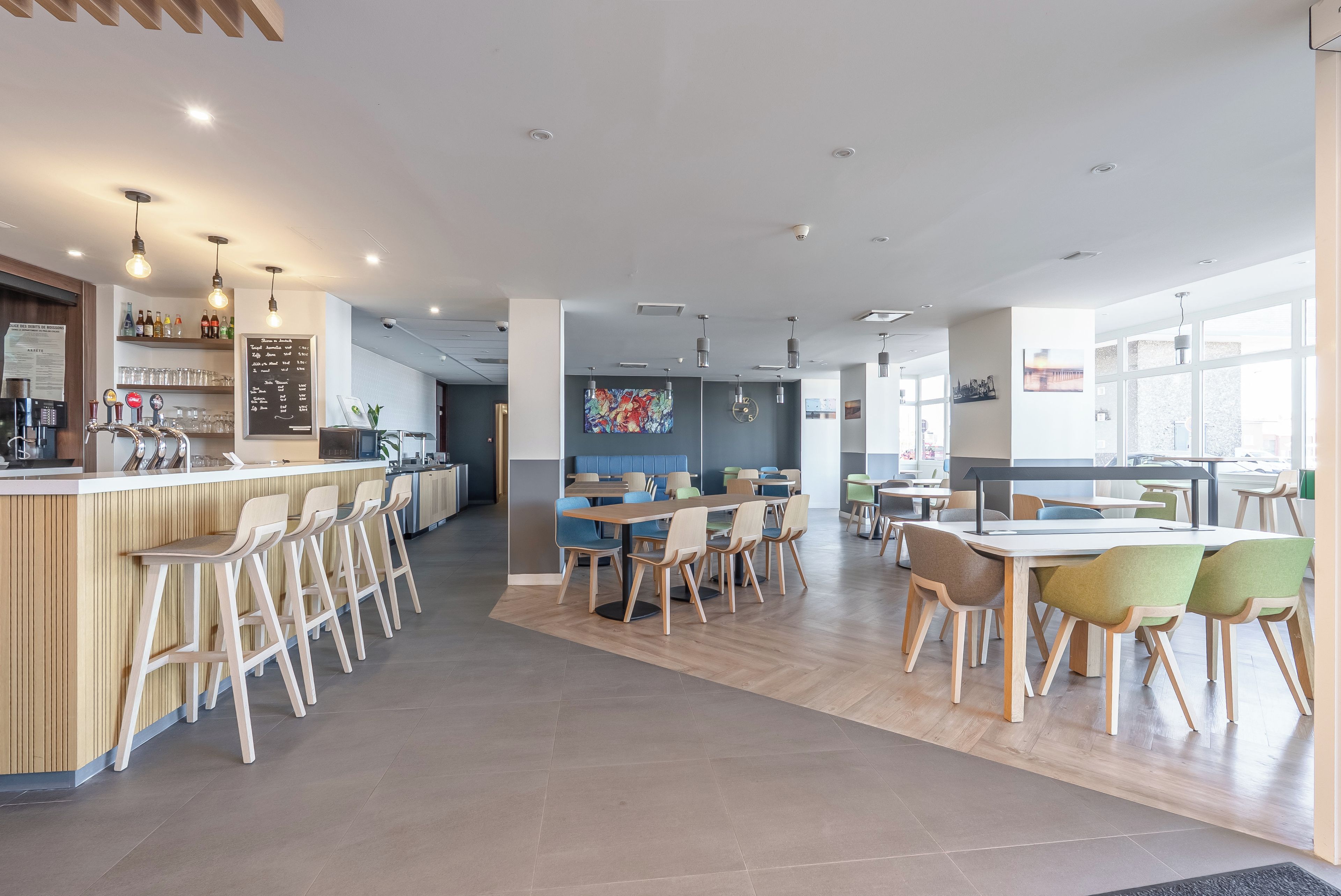 A modern cafe with a bar area, seating, and a menu board.