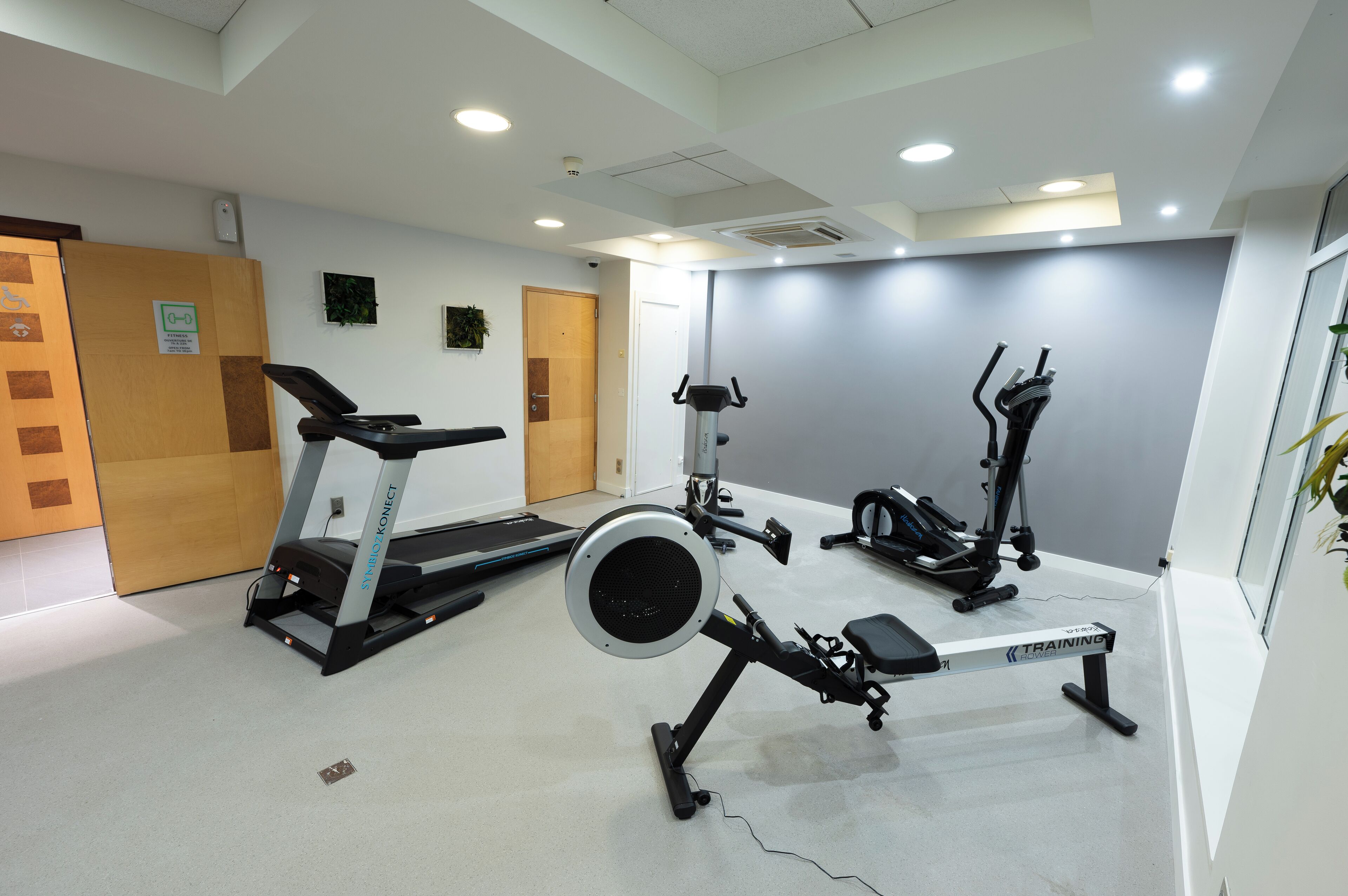 A gym with treadmills, elliptical machines, and a bench.