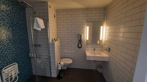 A bathroom with a shower, toilet, sink, and a mirror.