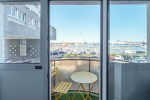 A balcony with a view of a marina, a table, and a chair. - Holiday Inn Calais - Centre Car Ferry by IHG (Calais)