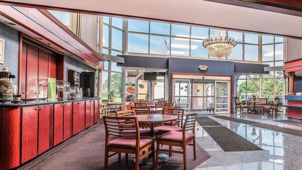 A spacious lobby with a bar area, a round table with chairs, and a chandelier. - Quality Inn & Suites Albany Airport (Latham)