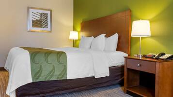 A hotel room with a bed, two bedside lamps, a nightstand with a phone, and a framed picture on the wall.