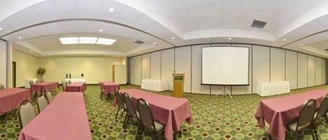 A conference room with tables, chairs, a podium, and a projection screen.