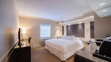 Ein Hotelzimmer mit Bett, Schreibtisch, Stuhl und einem großen Spiegel.