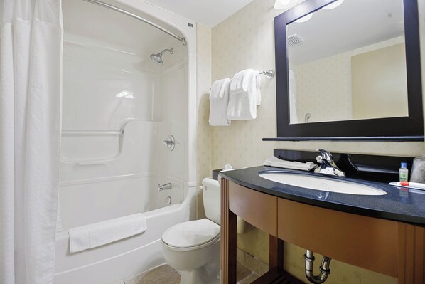 A bathroom with a bathtub, toilet, sink, and a large mirror.