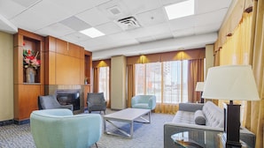 A hotel lobby with a fireplace, seating area, and large windows.