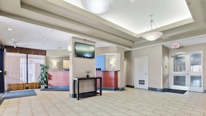 A spacious lobby with a reception desk, a television, and an exit sign.
