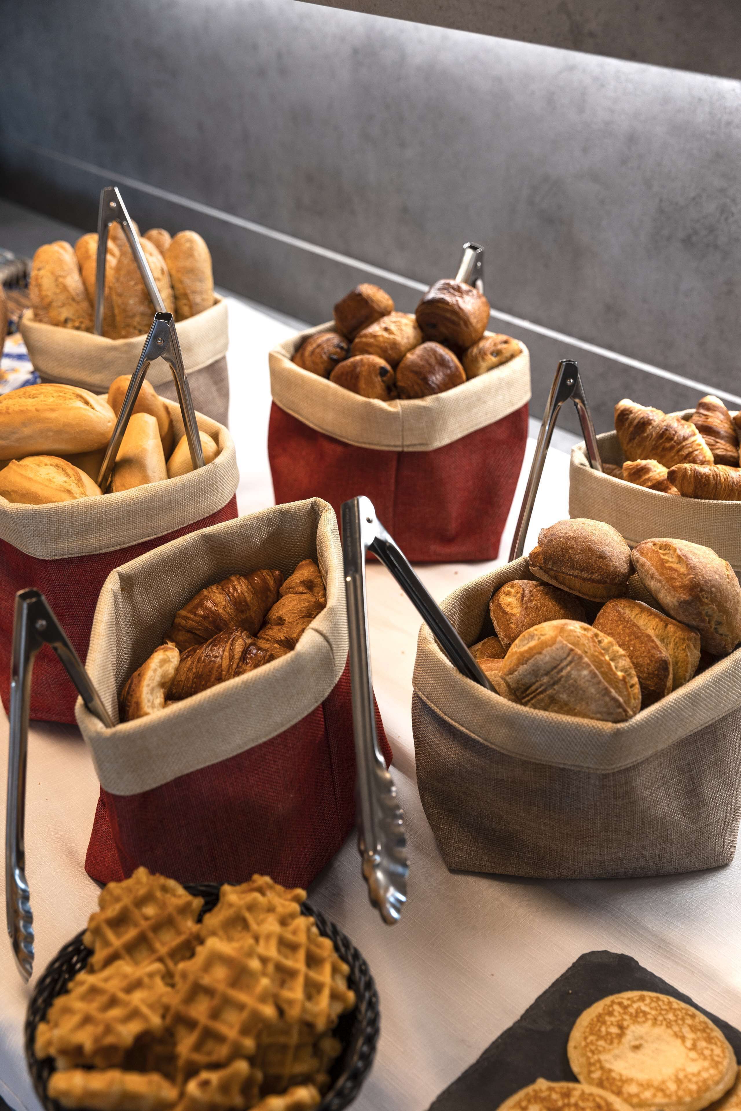 A variety of baked goods in baskets, including croissants and baguettes, arranged on a table.