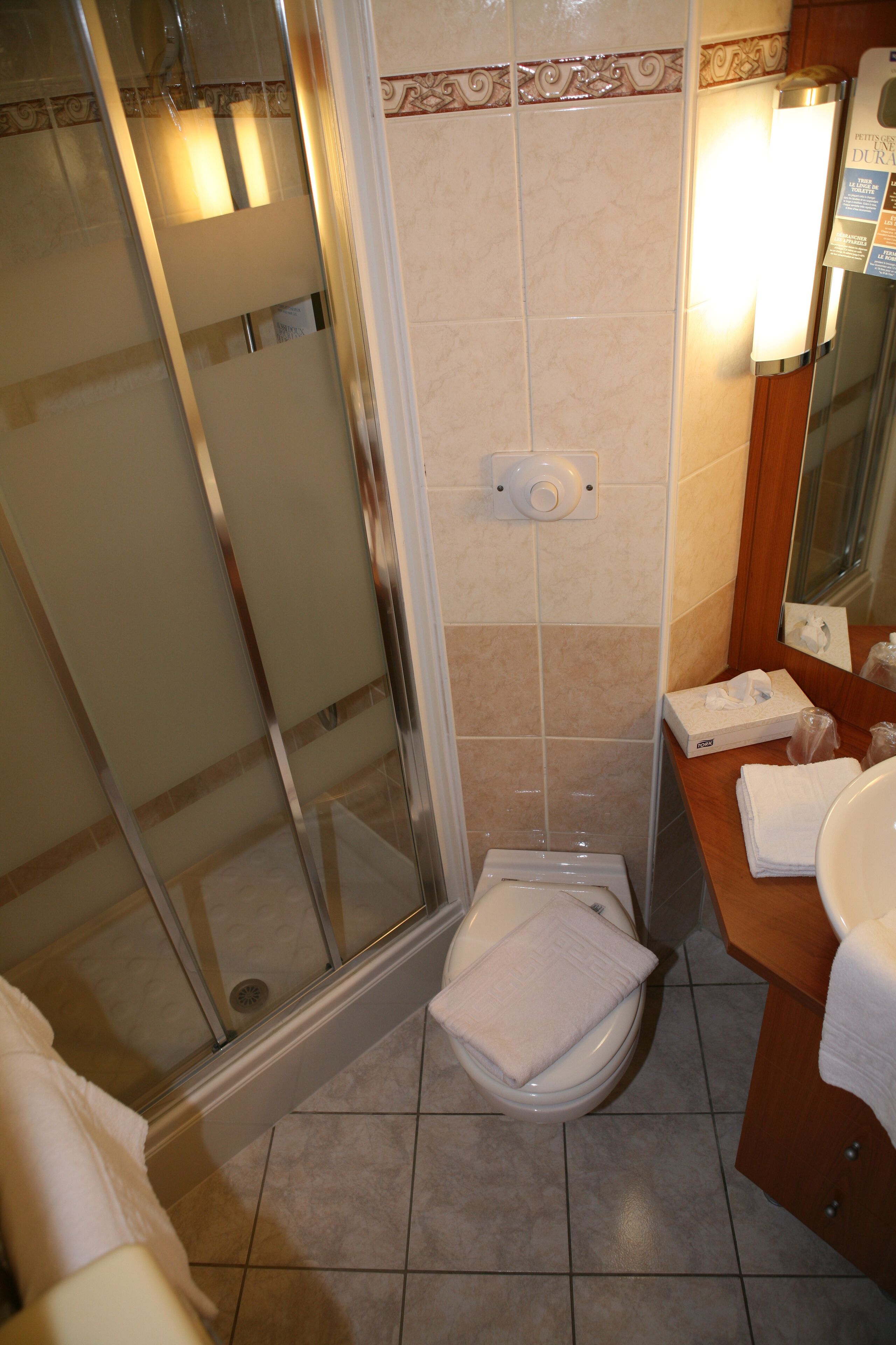 Un baño con cabina de ducha de vidrio, inodoro y lavabo con espejo.