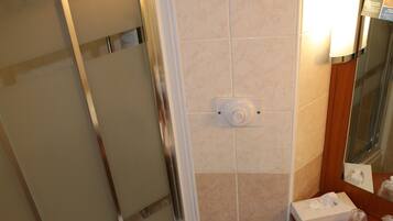 Un baño con cabina de ducha de vidrio, inodoro y lavabo con espejo.