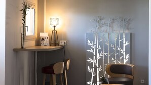 A modern room with a desk, two chairs, a lamp, and a decorative bamboo screen.