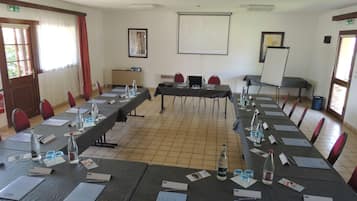 Une salle de conférence équipée de longues tables, de chaises, de porte-noms, de bouteilles d’eau et d’un écran de projection.
