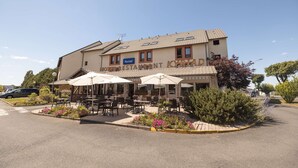 A hotel with outdoor seating and a sign reading "HOTEL RESTAURANT KYRIAD".