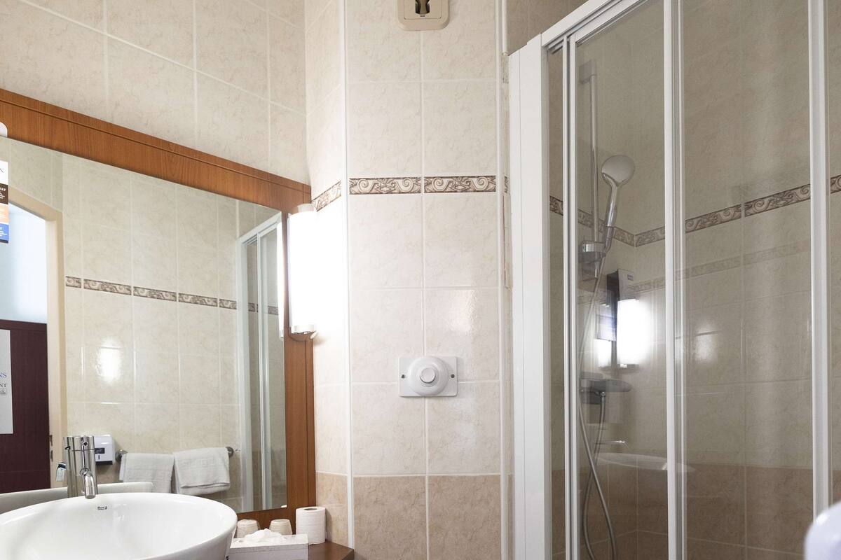 A bathroom with a large sink, toilet, and a glass-enclosed shower.