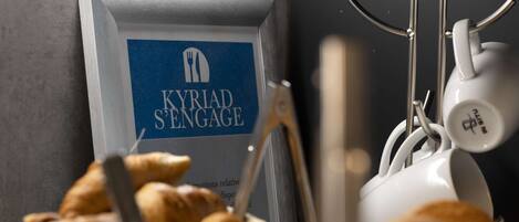 Un bufé de desayuno con cruasanes y un cartel que dice "KYRIAD S'ENGAGE".