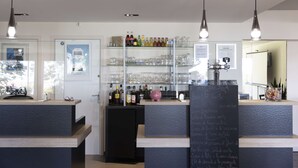 A bar area with shelves of bottles and glasses, a chalkboard menu, and pendant lighting.