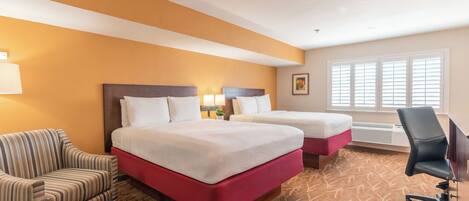 A hotel room with two beds, a sofa, a desk, and a chair.