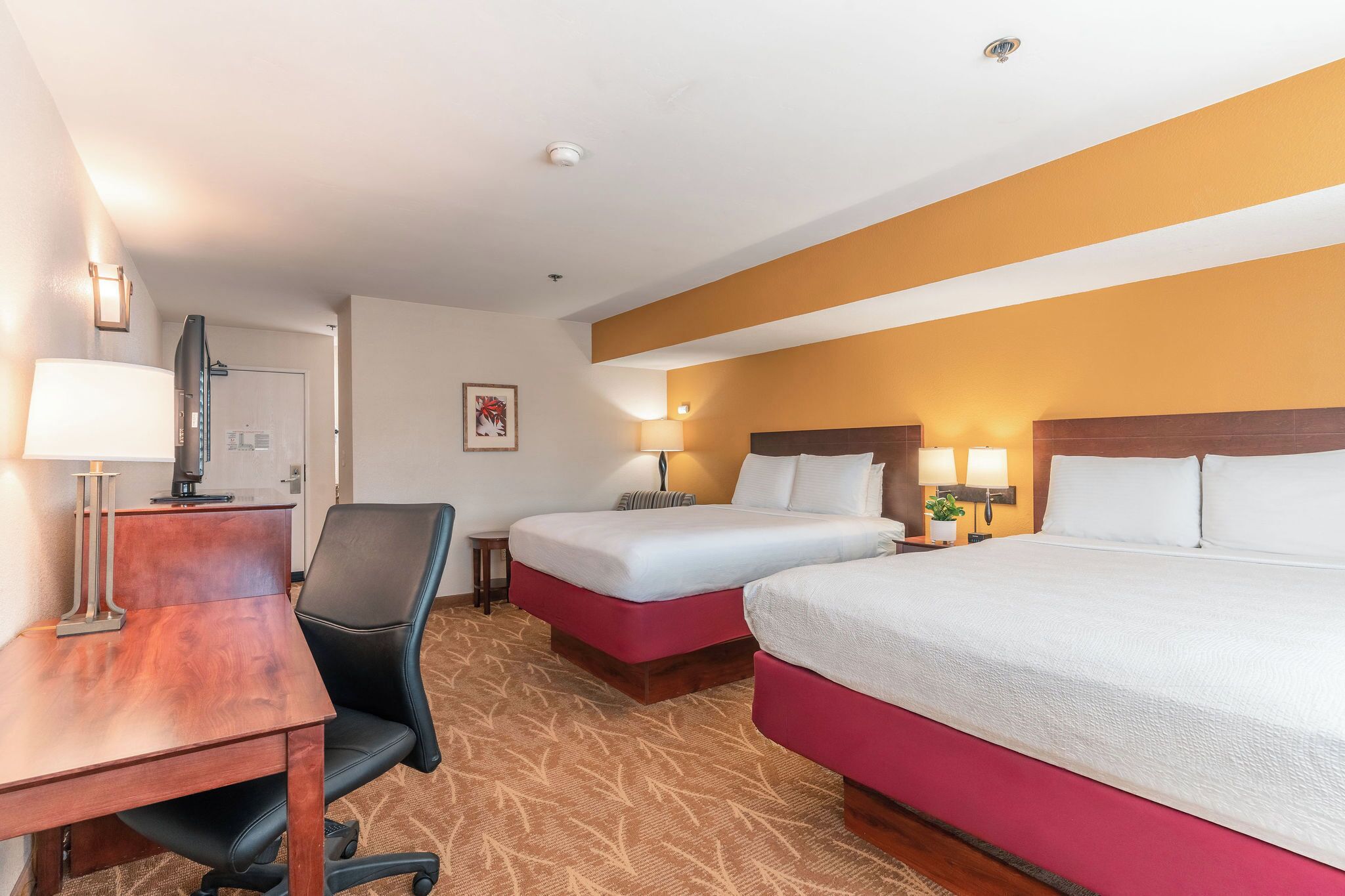 Een hotelkamer met twee bedden, een bureau, een stoel en een televisie.