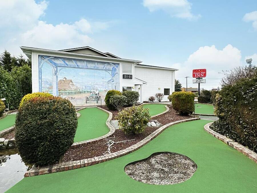 A miniature golf course with a mural, a white building, and a sign for Ocean Star Inn.