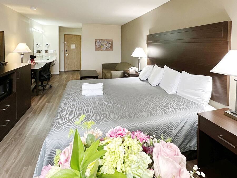 Una habitación de hotel con una cama grande, un escritorio, un televisor y un baño visible a través de una puerta abierta.