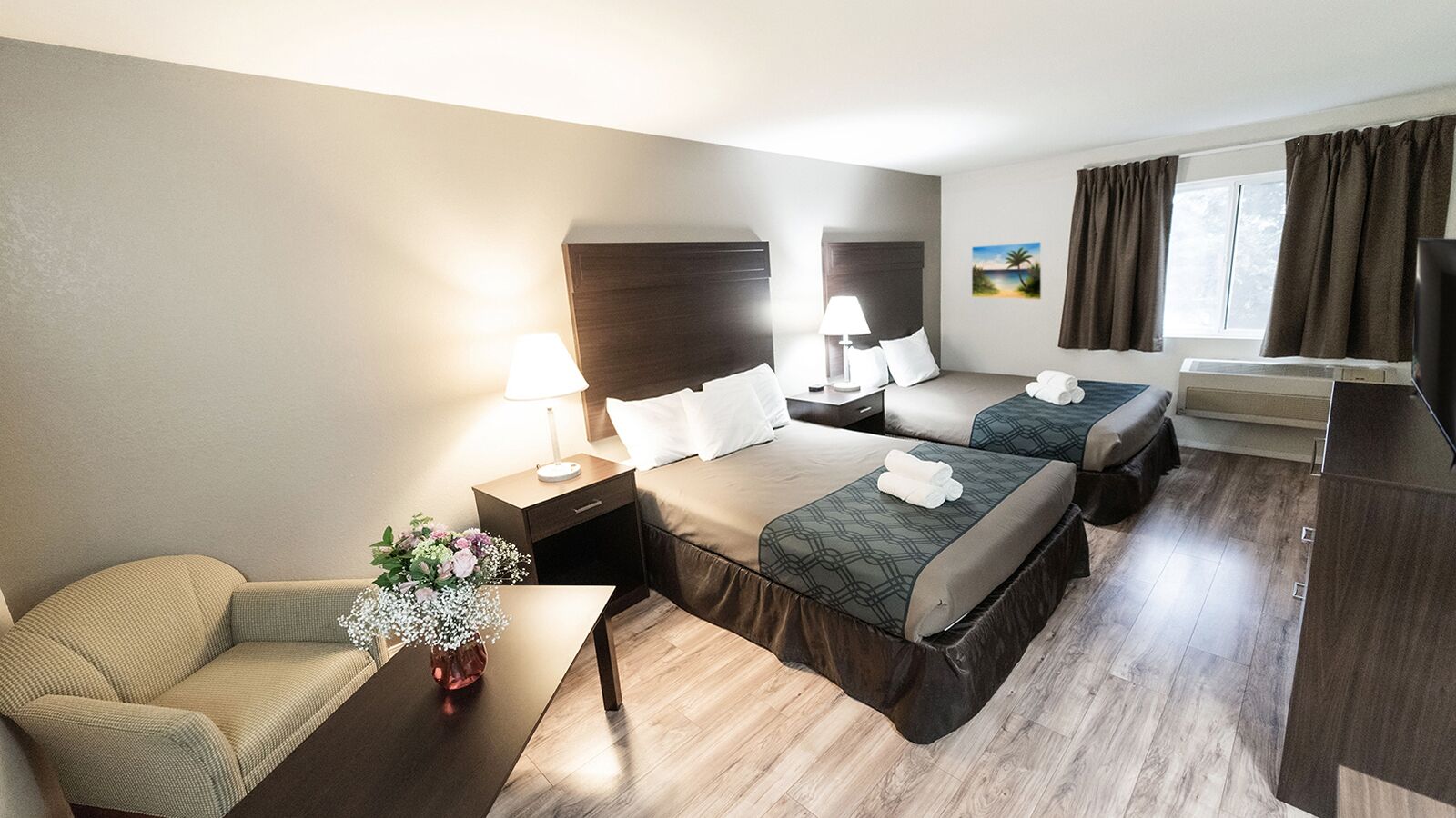 Een hotelkamer met twee bedden, een bank, een bureau en een nachtkastje met een lamp.