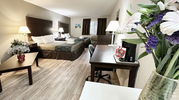Une chambre d’hôtel avec un lit, des tables de chevet, un bureau et une chaise. Un vase rempli de fleurs est posé sur le bureau.
