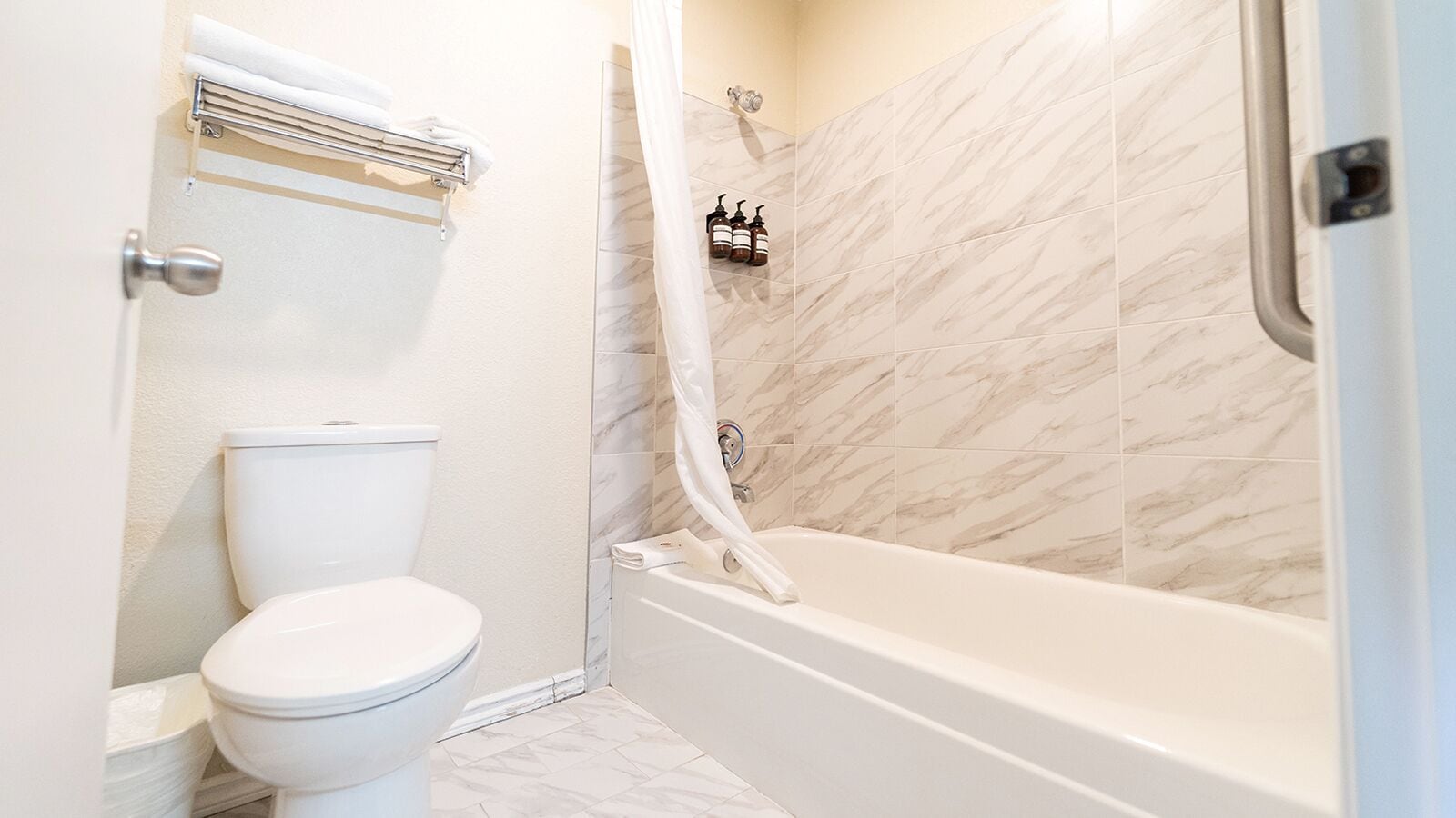 Een badkamer met toilet, douchegordijn en bad.