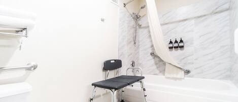 A modern bathroom with a shower, toilet, and a wheelchair-accessible bench.